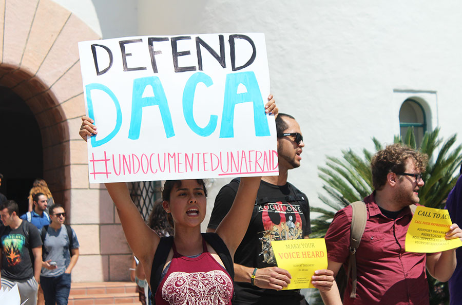 Estudiante de SDSU levanta cartel que lee Defende a DACA.