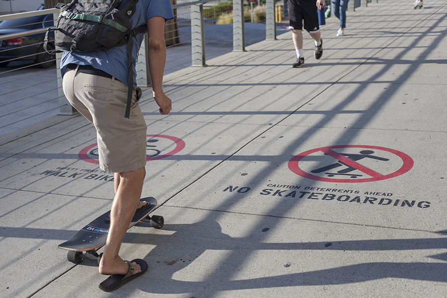 A skateboarder rides on a footbridge where it is not allowed.
