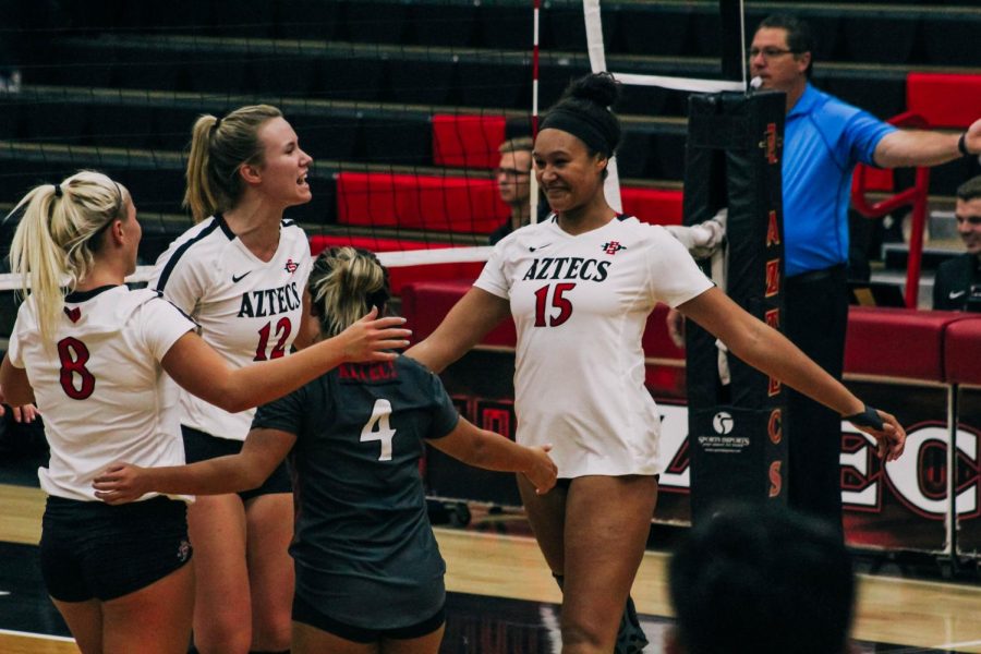 Senior middle blocker Deja Harris (right) celebrates with her teammates after earning a point during the Aztecs five-set loss to Louisiana on Sept. 15 at Peterson Gym.