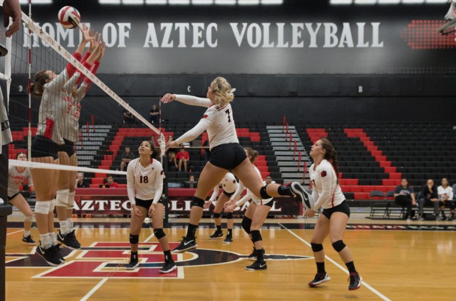 Junior outside hitter Hannah Turnlund spikes a ball over the outstretched arms of the Lobos defenders during the Aztecs four-set victory on Oct. 11 at Peterson Gym.