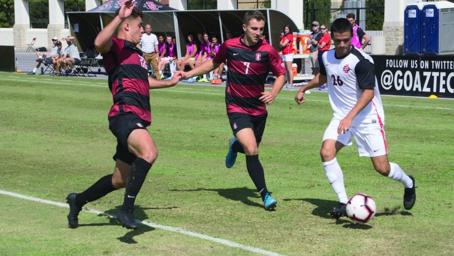 Freshman midfielder Blake Bowen attempts to get past two Stanford defenders during the Aztecs’ 1-0 loss to the Cardinal on Oct. 13 at the SDSU Sports Deck.