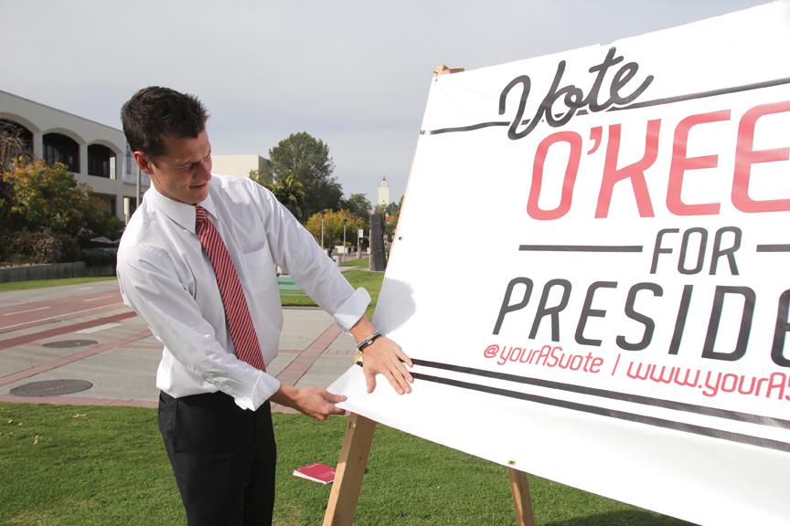 A.S. presidential candidate Rob O’Keefe fixes a campaign sign at the north end of Campanile Walkway. | Antonio Zaragoza, Photo Editor