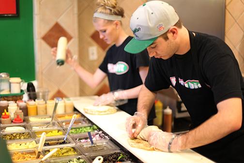 A Pita Pit employee rolls a stuffed pita. Several student employees will be left without a job.