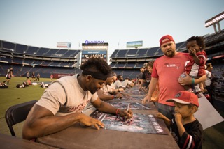 SDSU senior running back Rashaad Penny autographing a young fan's football poster at Fan Fest.