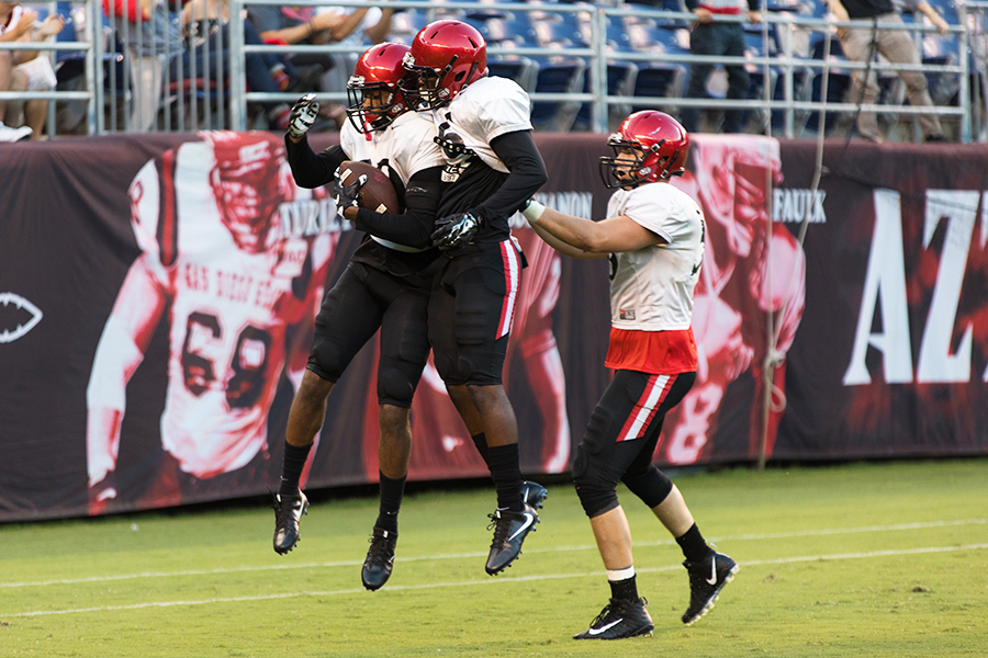 Three Aztec players celebrate after a touchdown by sophomore safety Jeff Clay during Fan Fest.