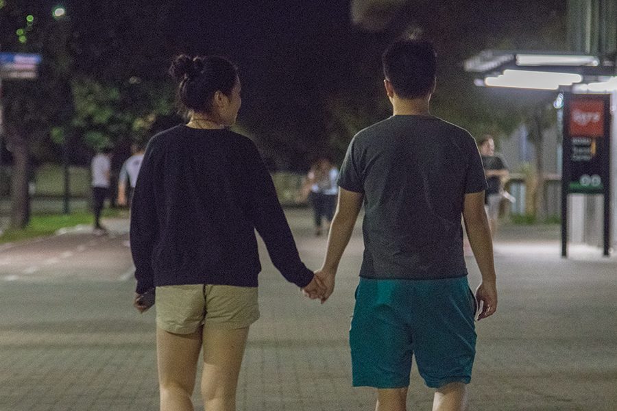 Sylvia Zhou and Tim Xu hold hands outside San Diego State trolley station.