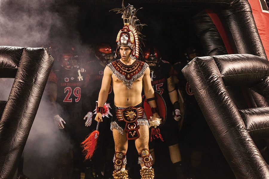 The Aztec Warrior mascot leads the football team on to the field. 