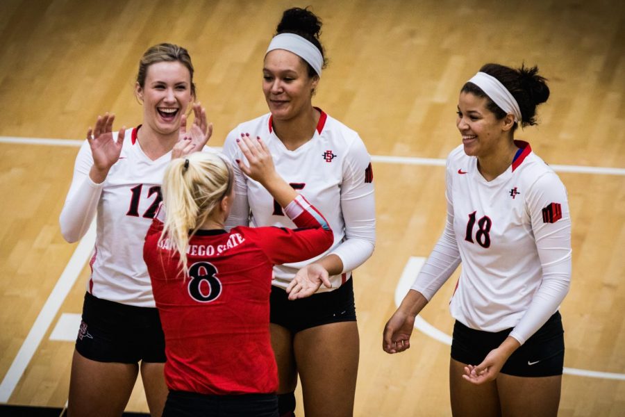 (Left to right) sophomore middle blocker Erin Gilchrist, senior middle blocker Deja Harris and junior middle blocker Tamia Reeves celebrate with redshirt sophomore defensive specialist Loren Teter (front) during the Aztecs three-set victory over Utah State on Nov. 1 at Peterson Gym.