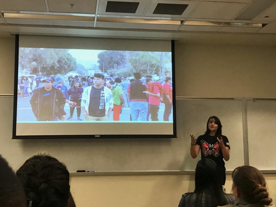 Border Angels Outreach Coordinator Leticia Guzman displays a photo of migrants in Tijuana on their first days in the city to a class at San Diego State on Dec. 10.