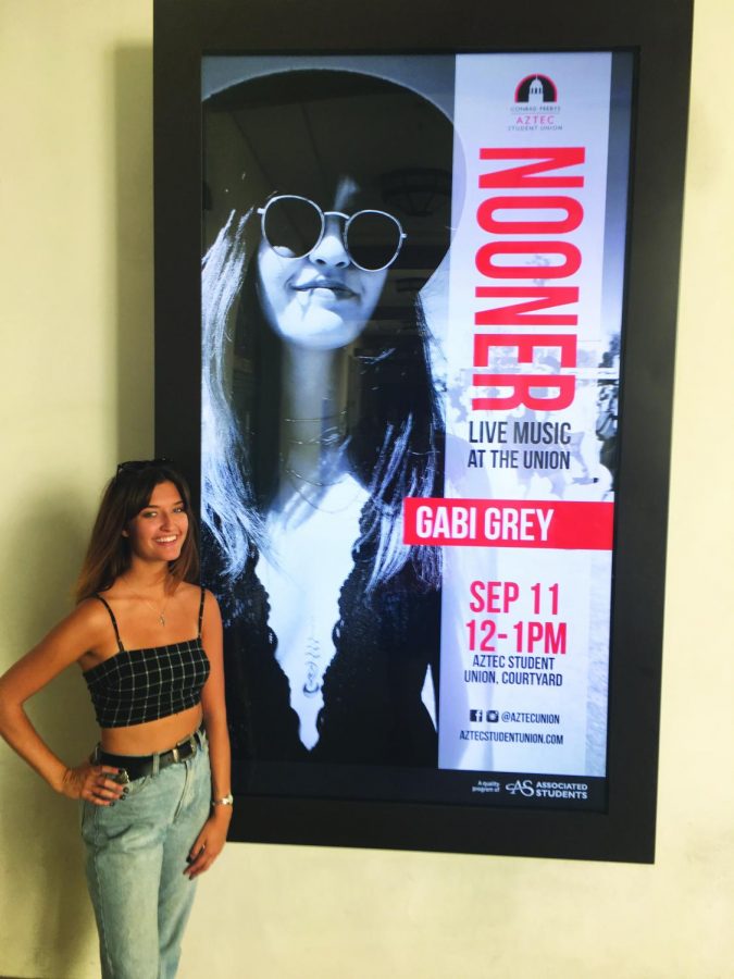 Budihas stands in front of her sign in the Aztec Student Union where she will be performing live on September 11.