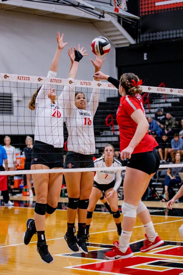 Junior outside hitter Lexie Hamrick (20) and senior middle blocker Tamia Reeves (18) attempt to block an attack from a UNLV player during the Aztecs 3-1 loss to the Rebels on Oct. 3 at Peterson Gym.
