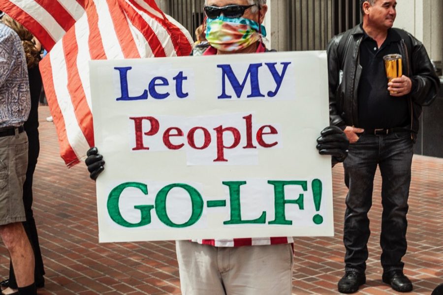 A protestor in Downtown San Diego holds up a sign in opposition to Newsom's stay-at-home order on April 18. The order has largely confined Californians to their homes since mid-March in an attempt to halt the spread of COVID-19.