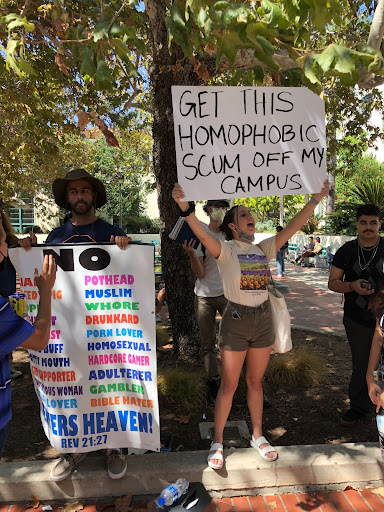 Student holds sign that reads Get this homophobic scum off my campus.