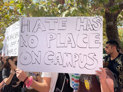 Student holds hand made sign that reads "Hate has no place on campus."