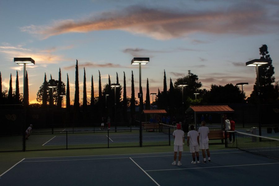Three+members+of+the+SDSU+mens+tennis+team+overlook+a+match+while+the+sun+sets+at+the+Aztec+Tennis+Center.