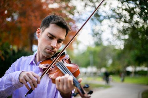Patrick Thelen, assistant journalism professor plays the violin near Scripps Cottage on Dec. 7. Thelen said of all the places at SDSU, he is going to miss walking this path on his way to his classes.