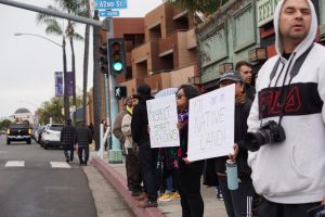 Community members hold signs in solidarity with Andres Arguelles-Alvarez, a street vendor who was recently harassed near the Viejas Arena, on Feb. 19.