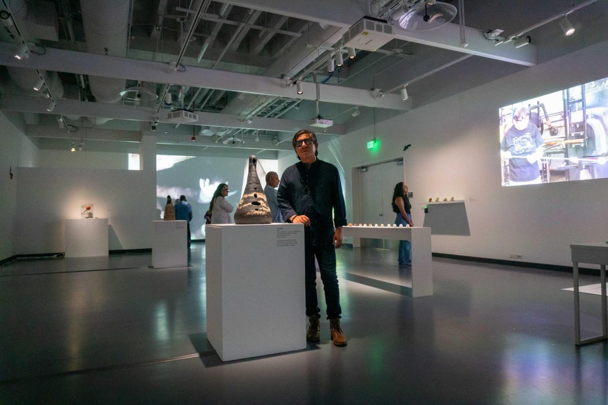 Francisco Eme, multimedia artist, poses with his exhibit at Mesa College Art Gallery. (Courtesy of Mesa College Art Gallery)