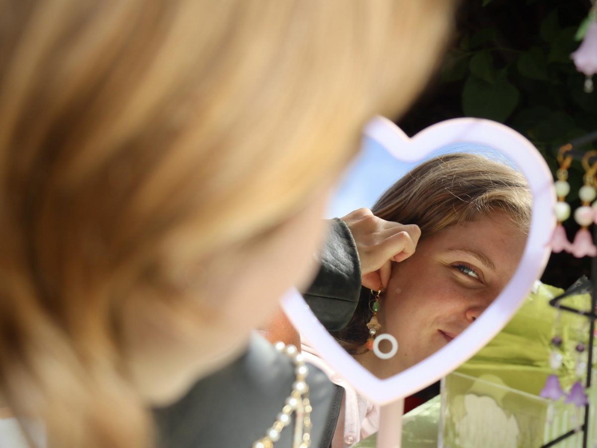 A customer tries on an earring from a jewelry vendor at the Fashion Club Market held on Sept. 29th at a house near campus.