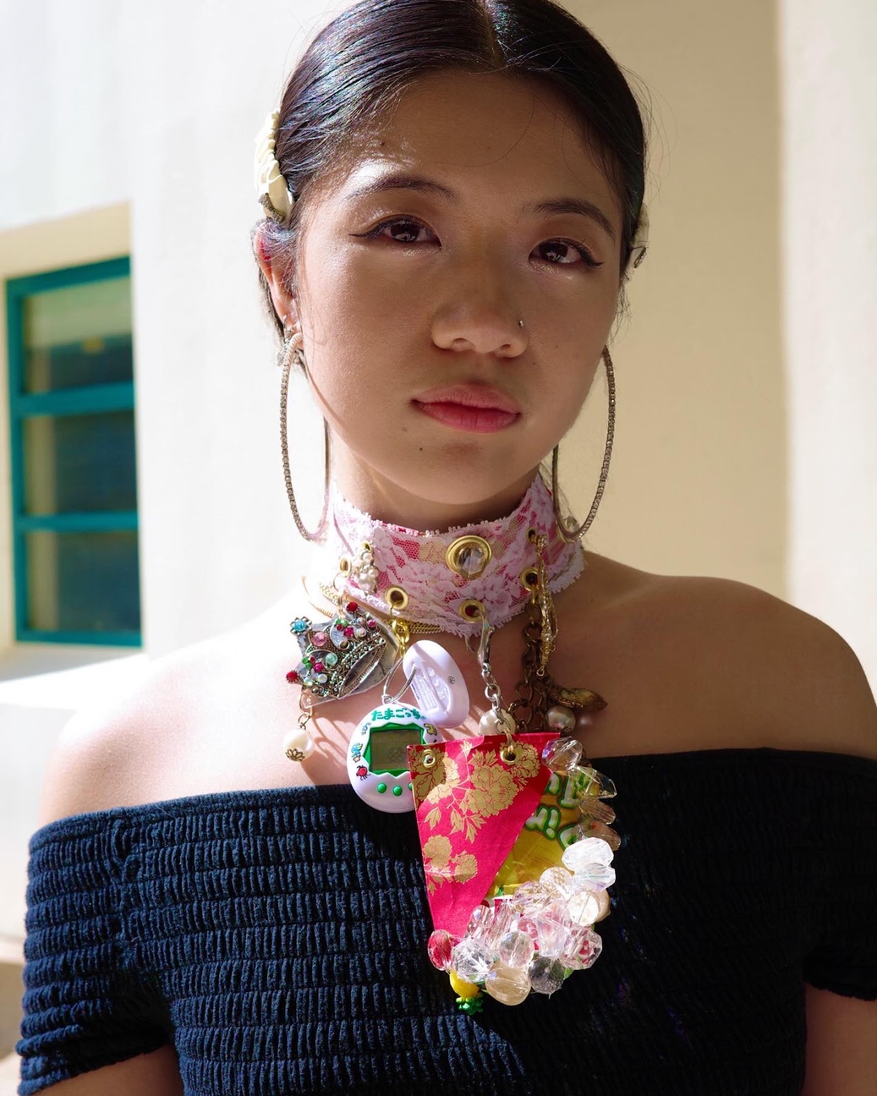 Hana Foo, a jewelry and metalwork major, wears  a necklace she made from a red packet, jewels, white lace, bracelets, crown charm, tamagotchi, CD and various costume scraps. (Photo Courtesy of Georgina Treviño)