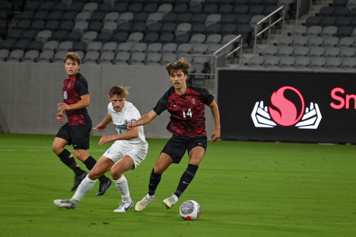 San Diego State defender Tristan Viviani (14) turns the ball away from a University of San Diego player on Saturday, Oct. 14 at Snapdragon Stadium.