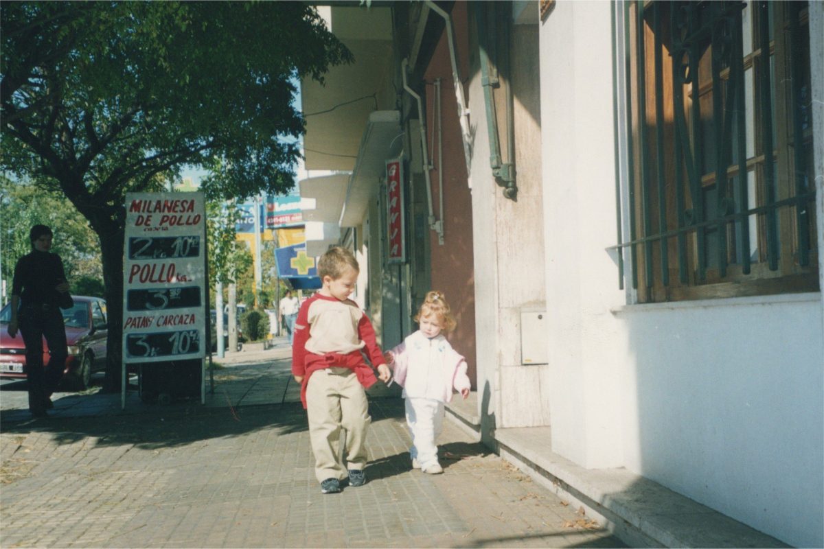 Ornella Rossi de dos años caminando con su hermano hacia el supermercado en Buenos Aires, Argentina.