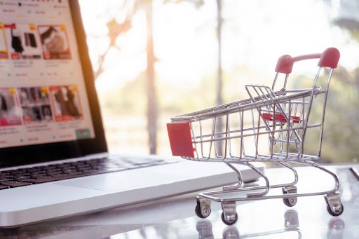Online shopping concept - shopping cart or trolley and laptop on table Free Photo