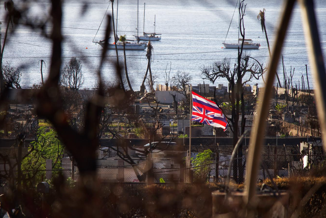 An upside down Hawaiian state flag flies in the midst of a burned down neighborhood in Lahaina, Maui. An upside down flag signifies a state of distress. Photo taken on Dec. 12, 2023.
