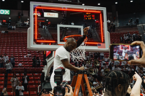 Adam Seiko cutting a piece of the basketball net as a keepsake from winning the Mountain West Regular Season Title against Wyoming in March, 2023 at Viejas Arena. 