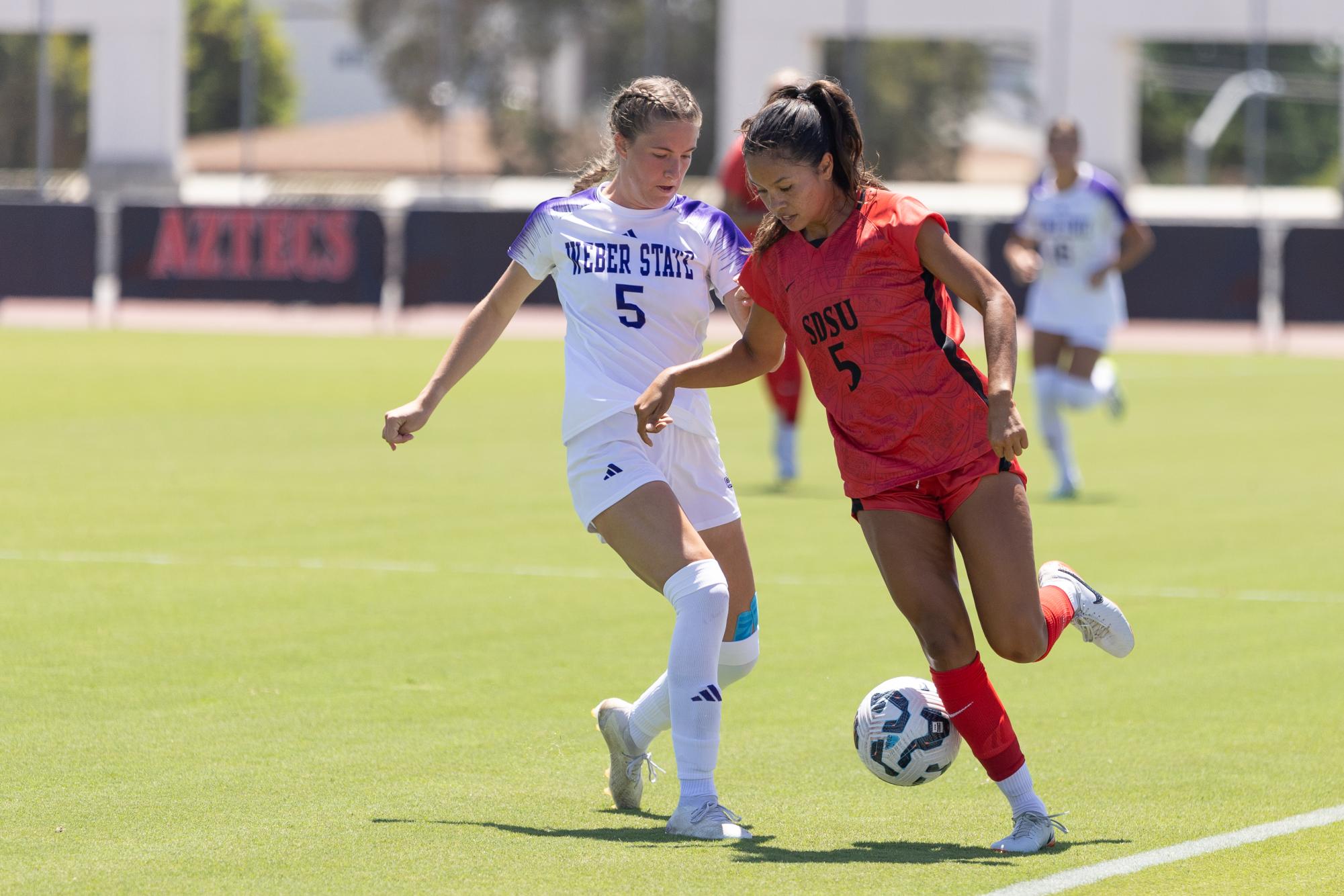 San Diego State forward Emma Gaines-Ramos tries to dribble down the sideline against the Weber State defender Lily Blum on Sunday, Aug. 18 at the SDSU SportsDeck. Gaines-Ramos was substituted out in the 52th minute and did not play the rest of the game.
