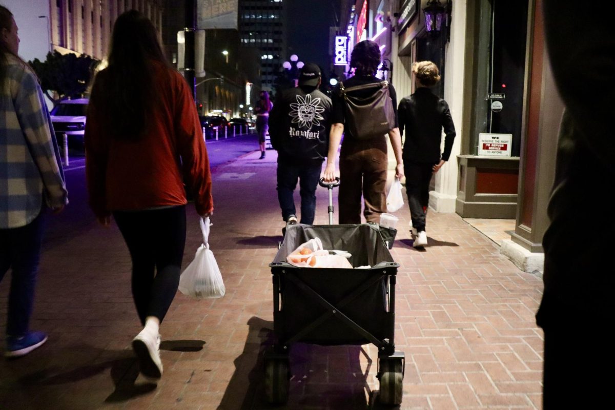 A group of volunteers with Streets of Hope pull a wagon through Gaslamp Quarter full of supplies to give out to the unhoused community on Feb. 26, 2024.