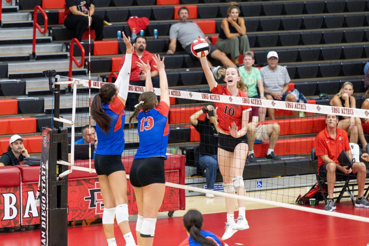 San Diego State outside hitter and opposite hitter Taylor Underwood spiking the ball over DePaul defenders at the Aztec Court inside Peterson's Gym on Thursday. Sept. 5.