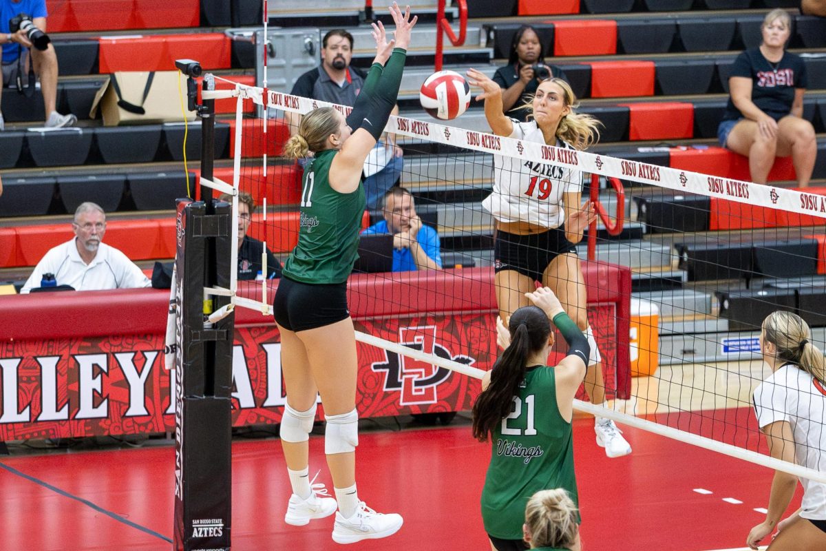 San Diego State opposite hitter Natalie Hughes dinks the ball over Portland State outside hitter Delaney Nicoll on Friday, Sept. 6 at the Aztec Court inside Peterson's Gym.