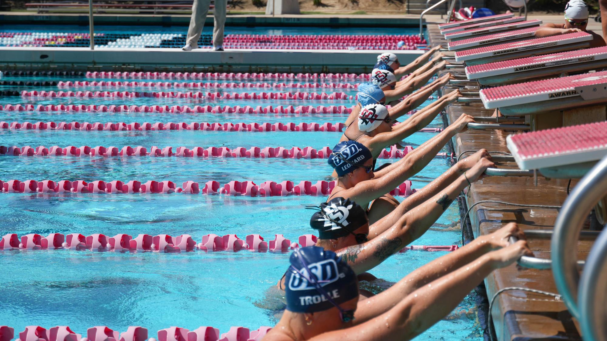 SDSU and USD backstroke swimmers prepare to dive in the 150 yard race on Sept. 27, 2024 at the Aztec Aquaplex.