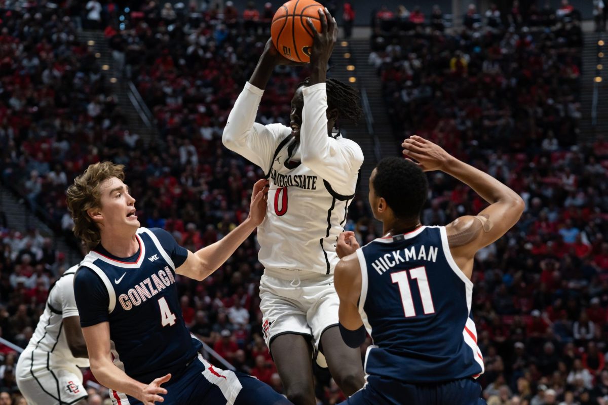 San Diego State freshmen forward Magoon Gwath drives up the court against Gonzaga’s sophomore Dusty Stormer (left) and senior guard Nolan Hickman (right) leading to a 80-67 loss on Monday, Nov. 19 at Viejas Arena. 
