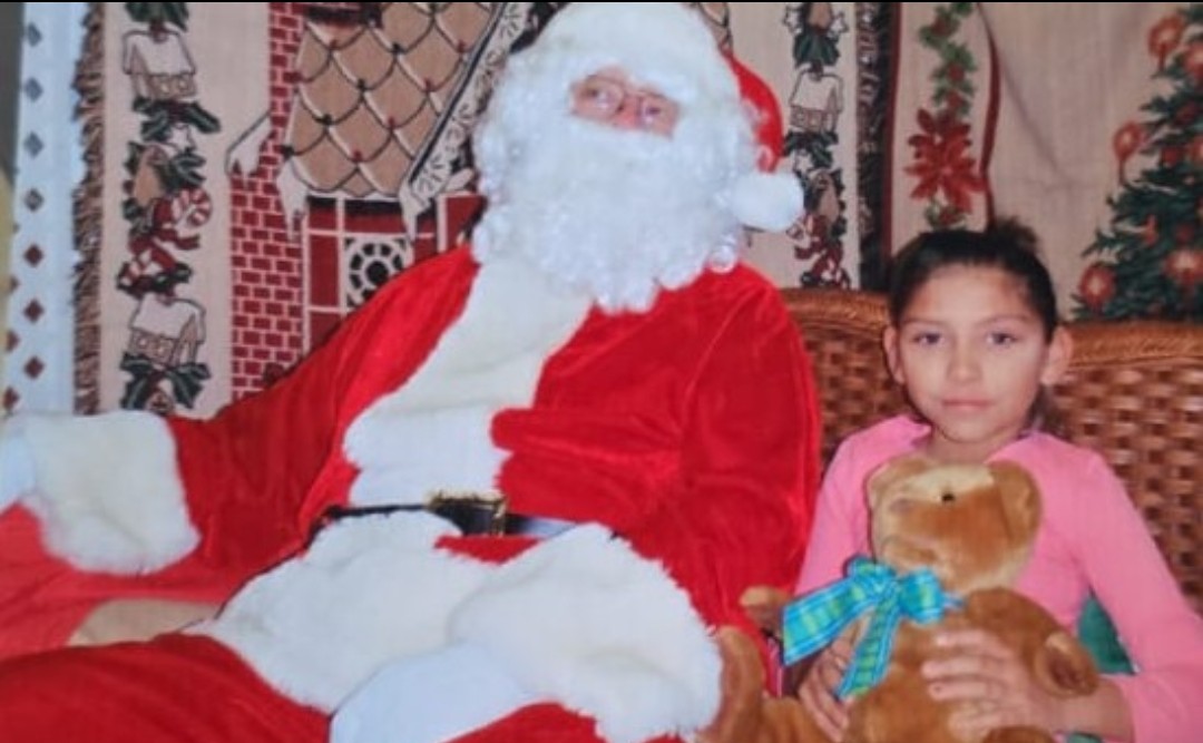 Esmeralda Hernandez Cardenas, con un peluche en sus manos, sentada junto a Santa Claus.