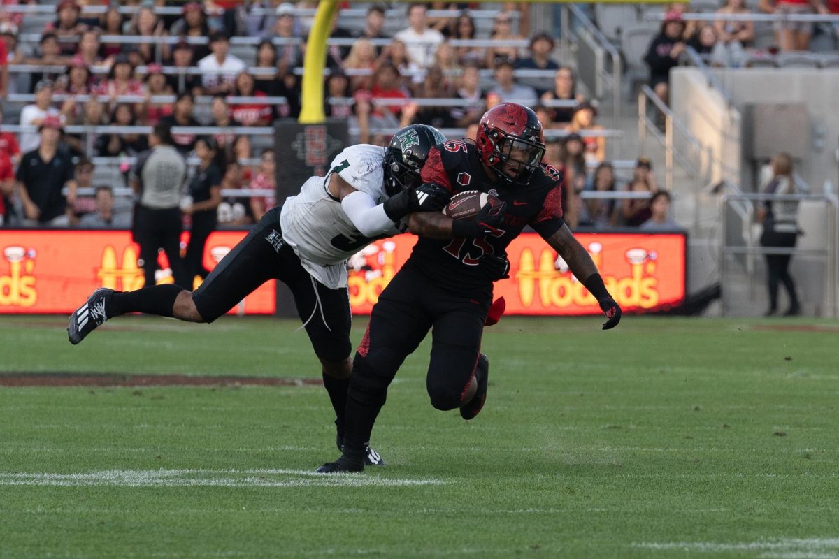 Former San Diego State running back Marquez Cooper embraces contact as he's tackled by a Hawaii defender at SnapDragon Stadium during a game last season on Saturday October 5, 2024.

