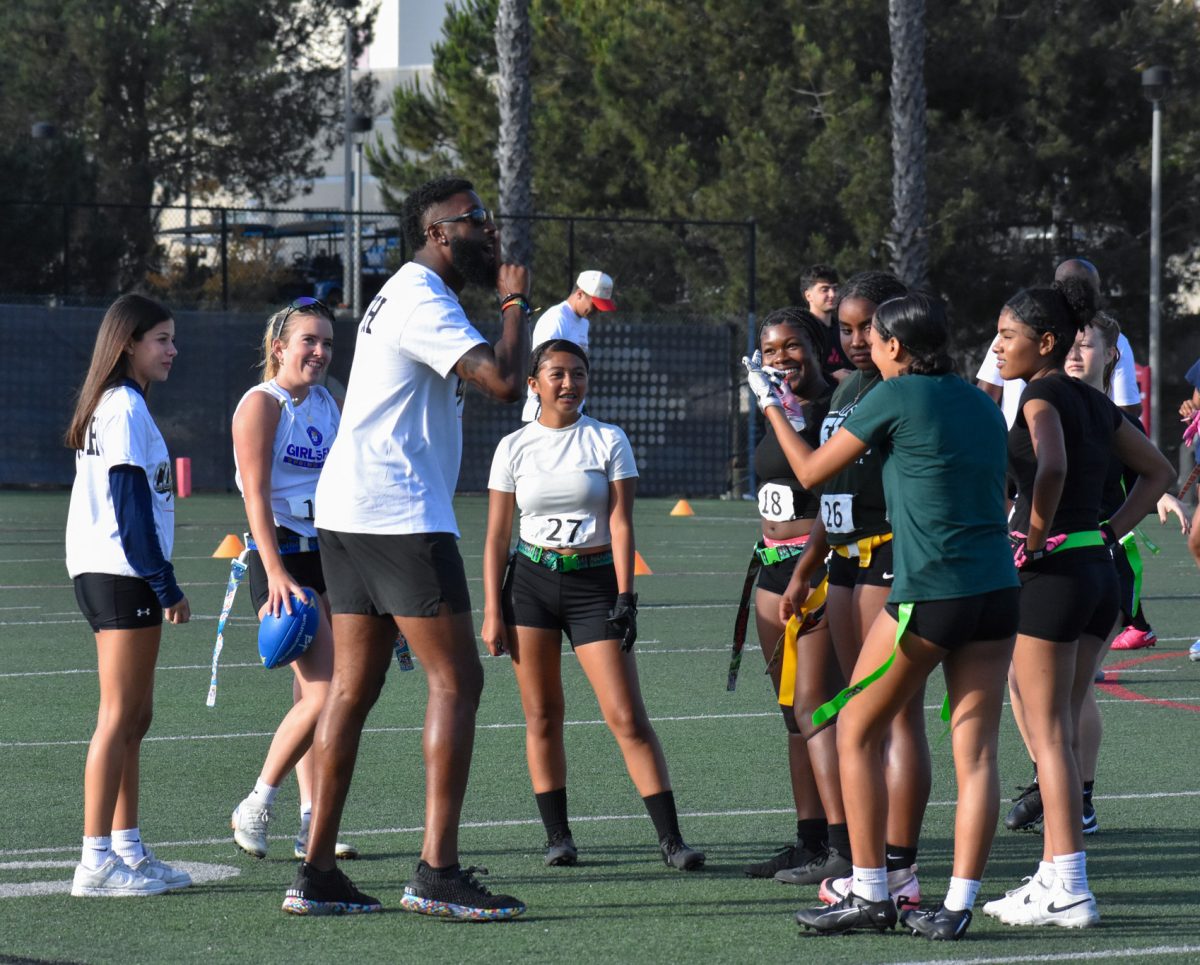 NIL Aztec Link Coach connects with student-athlete participants in a cheerful conversation between exercises on Saturday June 21, 2025 at the PG 610 field.