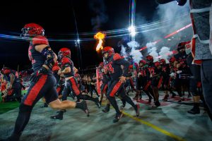 The San Diego State football team runs of out of the tunnel before a game at SnapDragon Stadium last season.
