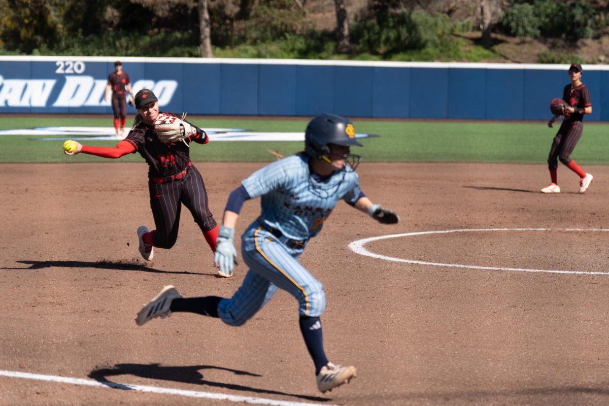 San Diego State senior utility Angie Yellen (24) throws the ball toward home to get Kansas City sophomore infielder Ella Husak out in a 10-2 win over Kansas City, Saturday, Feb. 28, 2026, at USD Softball Complex, San Diego, CA.