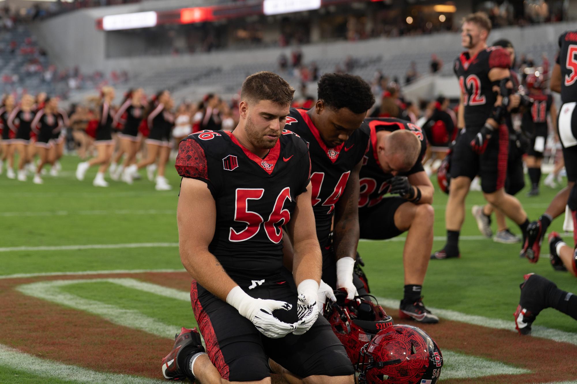 Junior defensive lineman August Salvati gets on his knees and prays before the season opener against Stony Brook on August 28, 2025, at Snapdragon Stadium. 