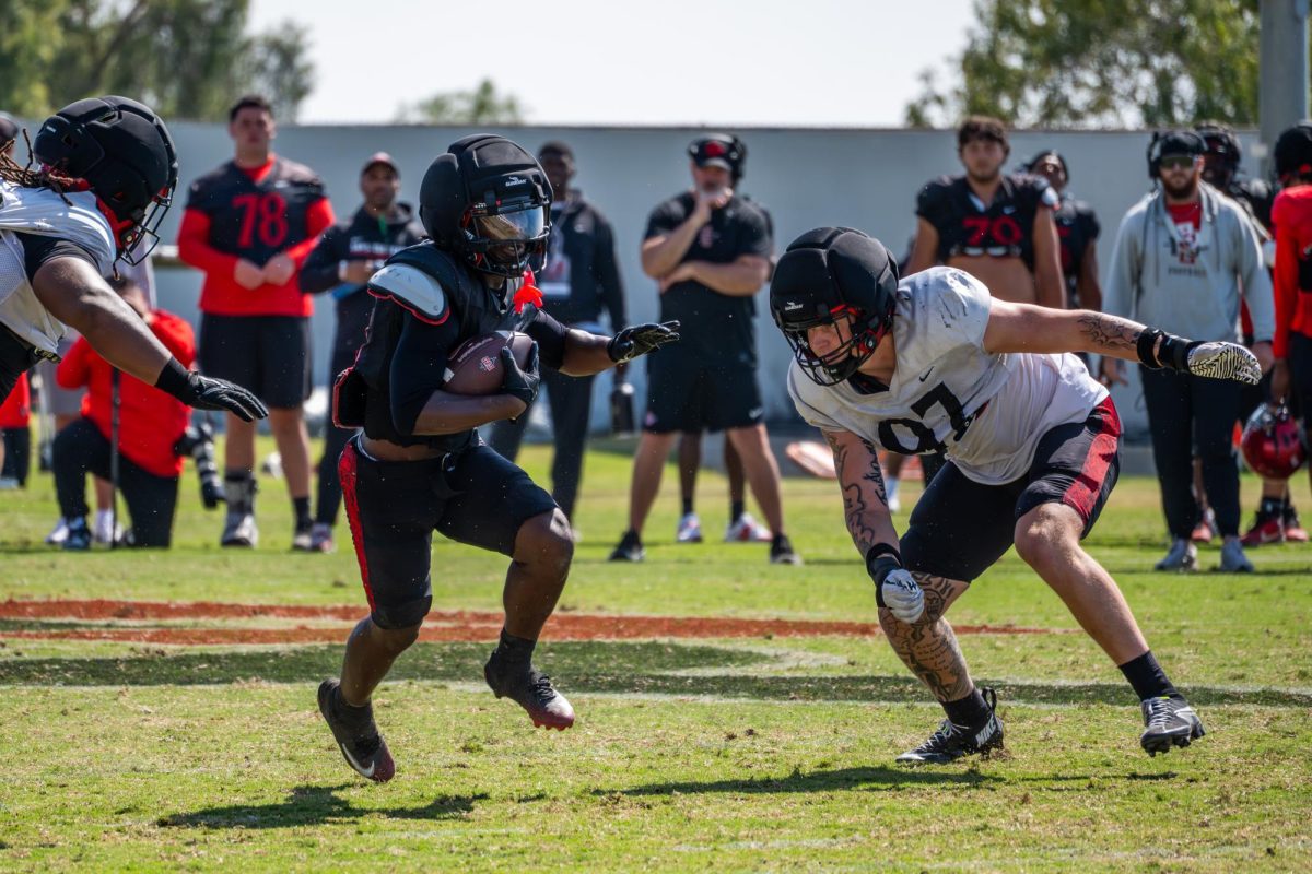 Running back Javion Kinnard (21) cuts between two defenders at the Aztec spring game on Tuesday, May 2, 2026, at San Diego state university 