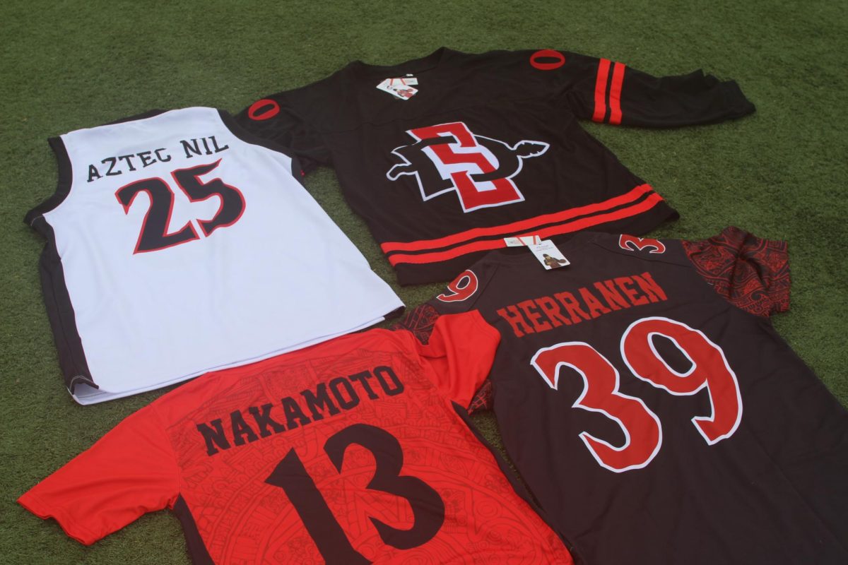 978 Jerseys and student-athlete branded shirts lay across the ENS Field at San Diego State University on Friday, May 15, 2026. 