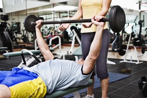 A spotter ensures a weight lifter doesn’t injure himself while training. This is one of the many roles athletic trainers take on in the exercise and nutritional sciences.dept. Thinkstock
